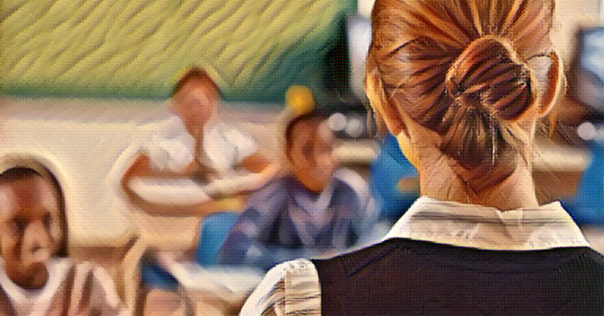 female teacher wearing a bun, her back turned to us, faces her class of students, sitting attentively in their desks