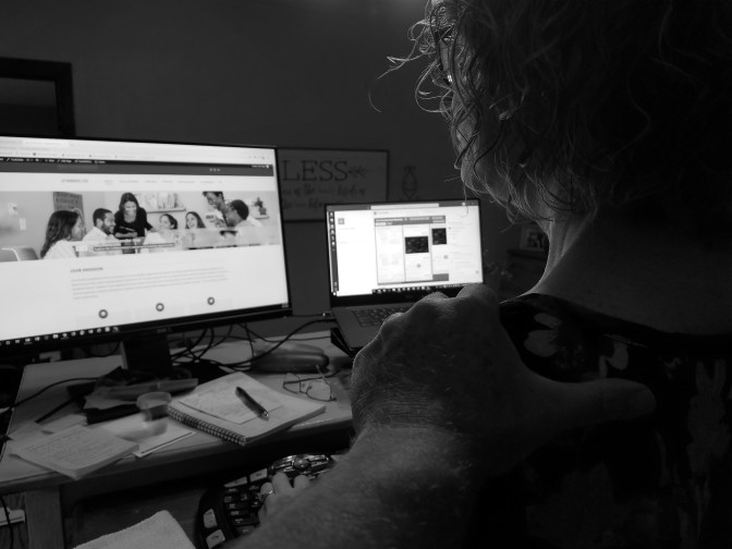 a man reaches out to touch the shoulder of a woman working from home