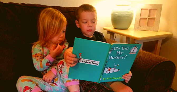 Young boy reads the book Are You My Mother to his little sister