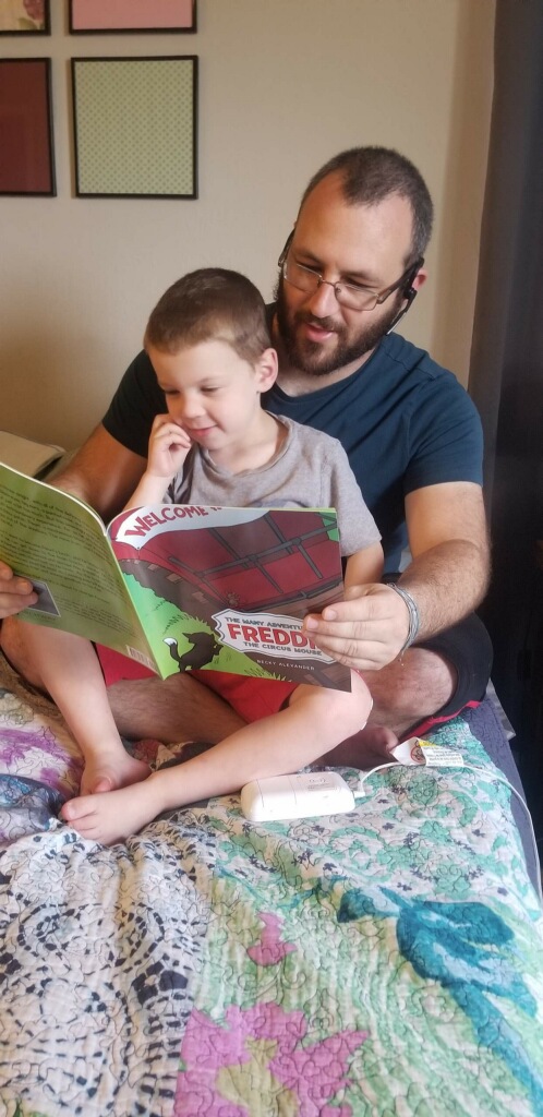 Niko and his father Jim enjoy the illustrated children's book The Many Adventures of Freddie the Circus Mouse by Becky Alexander