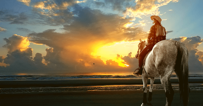 A woman rides on horseback on the beach as the sun rises, displaying God's glory