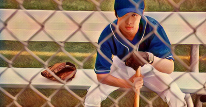 Young baseball player sits the bench, bat in hand, glove beside him, longing to play the game.