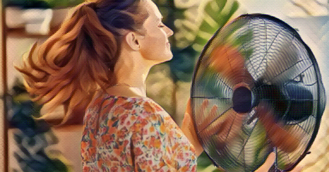 woman stands in front of a fan to get cool