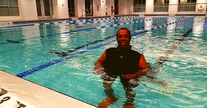Coach Marion Chisholm water walking in the swimming pool at Gainesville Health & Fitness. In the other lanes during this early-morning photo, swimmers are doing freestyle and backstroke in the background.