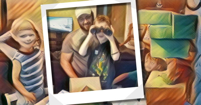 Niko joyfully peers through his new set of binoculars, his dad smiling behind him.