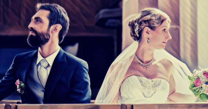 A bride and groom in full wedding regalia are looking away from each other.