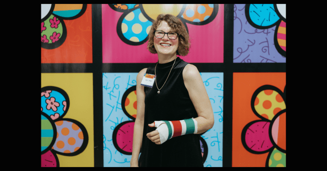 Sara splinted against a backdrop of art by Roberto Britto