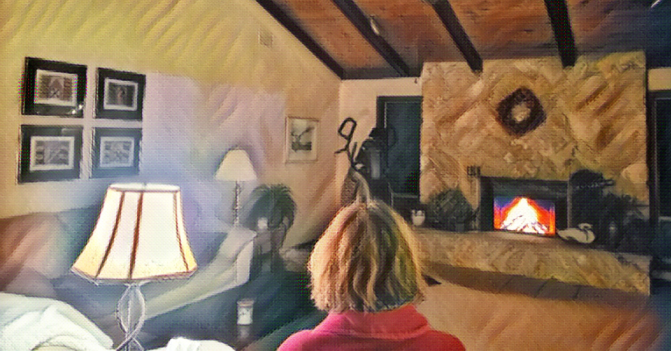 a family room with a fire in the fireplace and the back of a woman's head